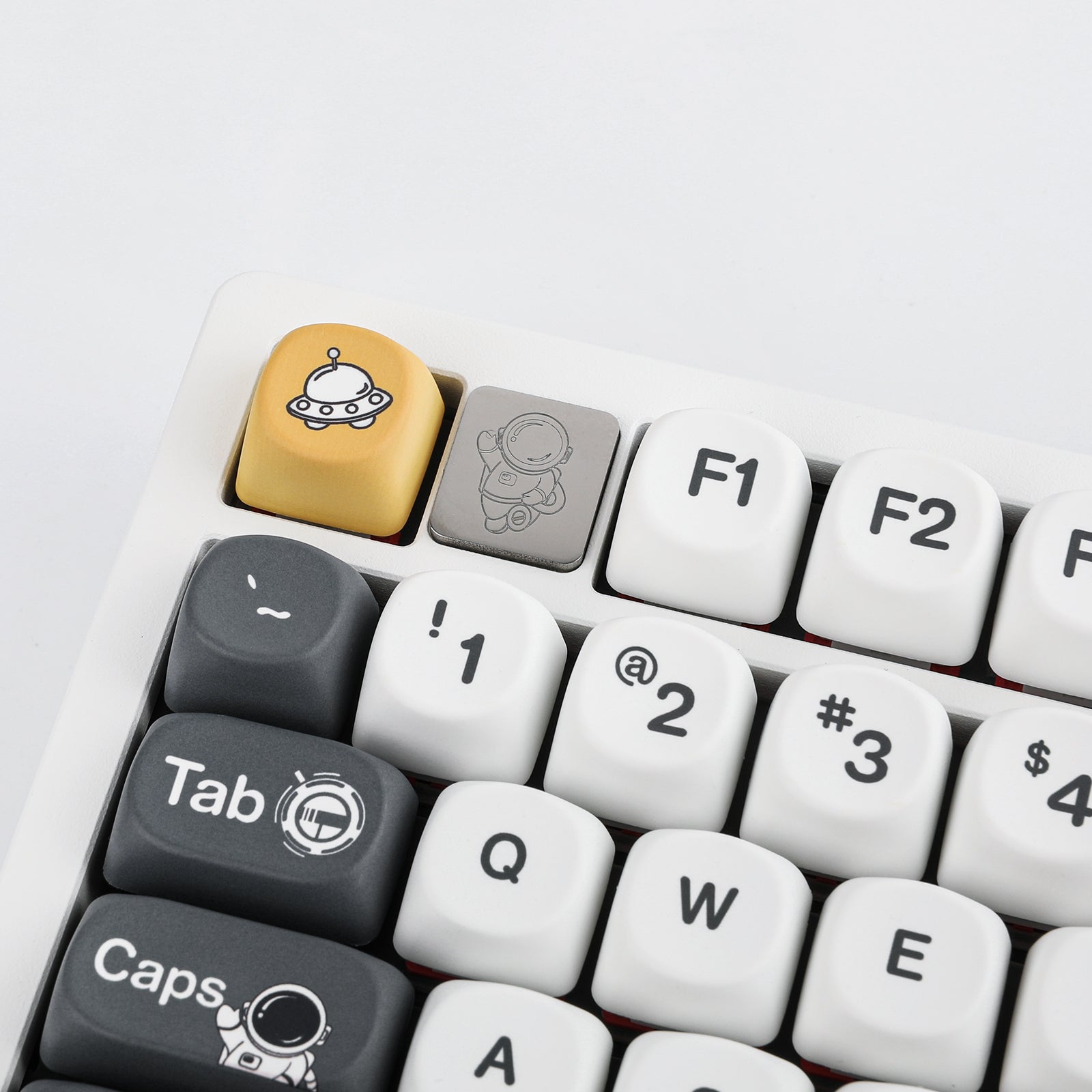 Macro shot of the yellow UFO Esc keycap and engraved metal astronaut keycap